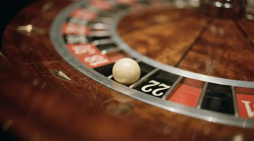 A white roulette ball rests in the number 22 slot on a wooden roulette wheel