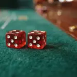 A close-up, low-angle photograph of two casino dice resting on deep green baize, their pips sharply in focus