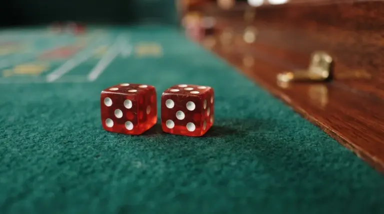A close-up, low-angle photograph of two casino dice resting on deep green baize, their pips sharply in focus