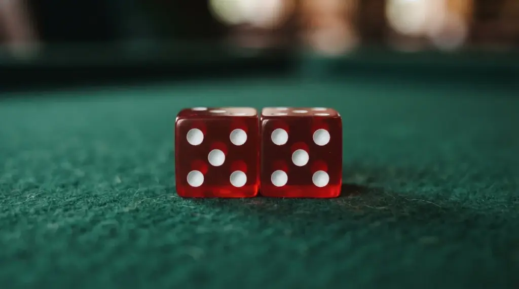 Two red five-sided dice resting on a green felt surface