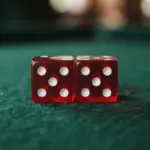 Two red five-sided dice resting on a green felt surface