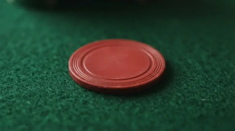 A plain red circular gaming chip rests on a green felt surface