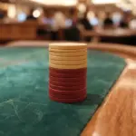 A shallow depth of field close-up photograph of a neat, short stack of plain casino chips precisely placed on deep green